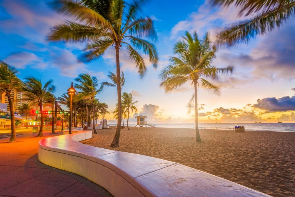 Praia em Fort Lauderdale, destacando palmeiras, a areia e o horizonte do mar