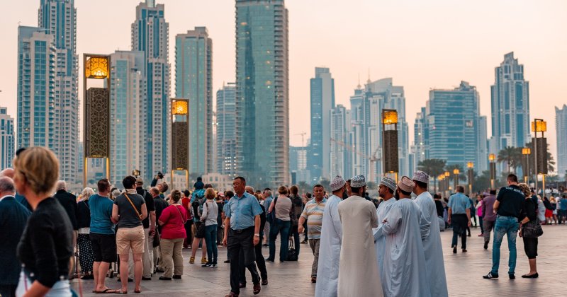 Fluxo de pessoas numa rua em Dubai, com os prédios imponentes ao fundo