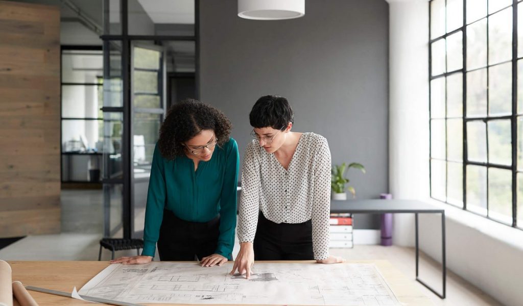 Duas mulheres discutindo um projeto sobre a mesa. Escolhendo o destino perfeito para estudar arquitetura