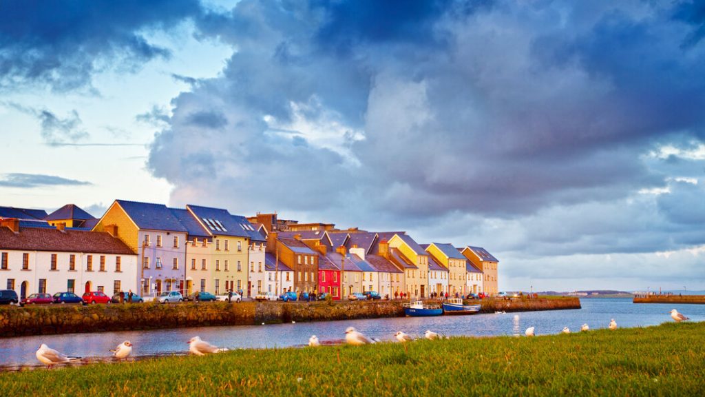 Visão ampla de Galway com suas casas coloridas e o mar.