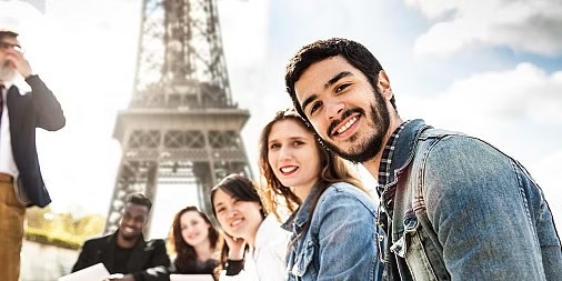Vários estudantes de diferentes nacionalidades olhando para a foto à base da torre Eiffel. Ensino superior na França.