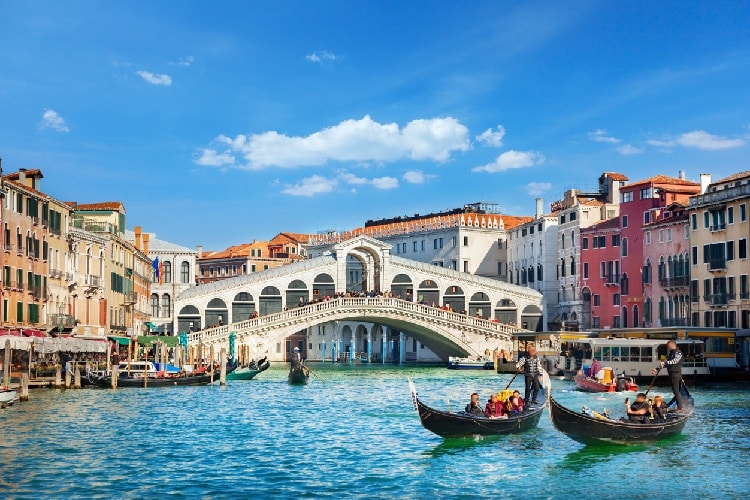 Dia ensolarado num canal sob ponte em Veneza, na Itália