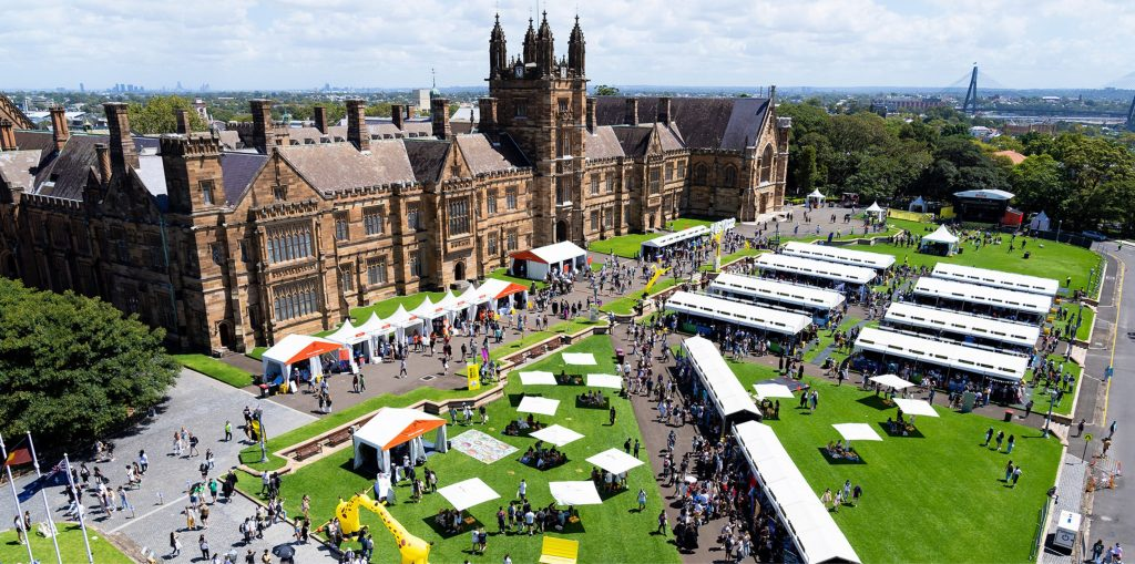 Vista aérea da Universidade de Sydney, durante uma feira estudantil recebendo diversos estudantes.