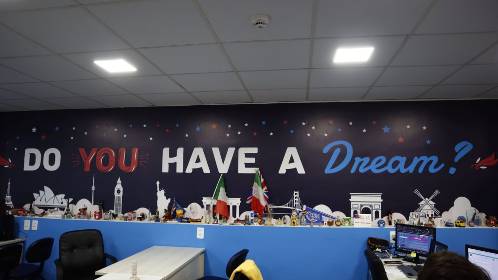 Imagem interna do escritório sede da Dreams Intercâmbios com os dizeres "Do you have a Dream?" adesivados na parede.
