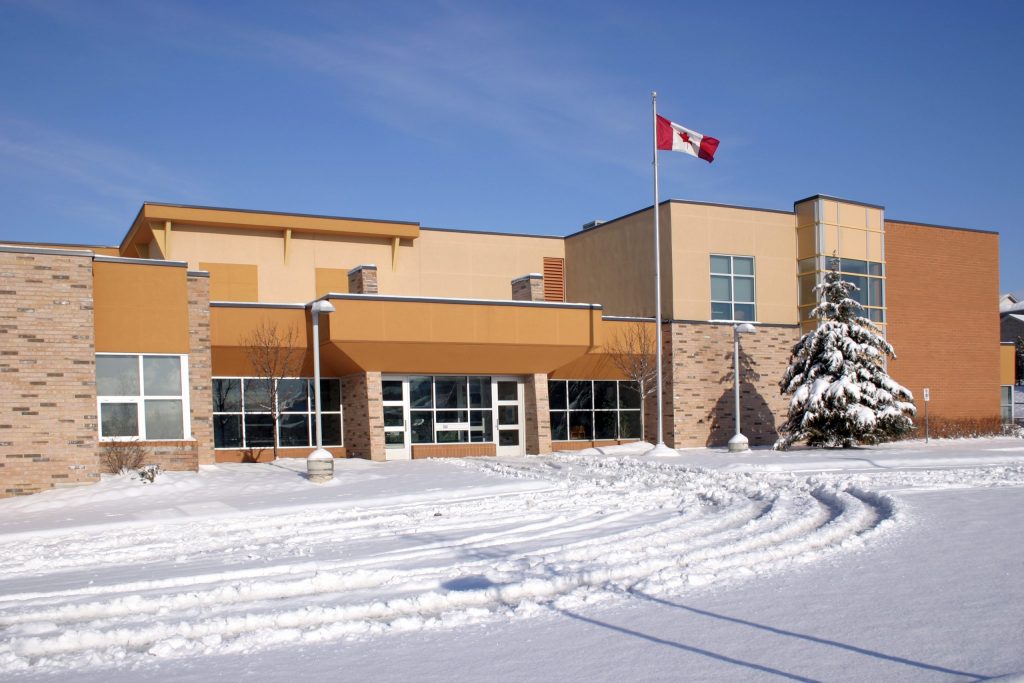 Fachada de uma escola de ensino médio no Canadá no inverno, com neve