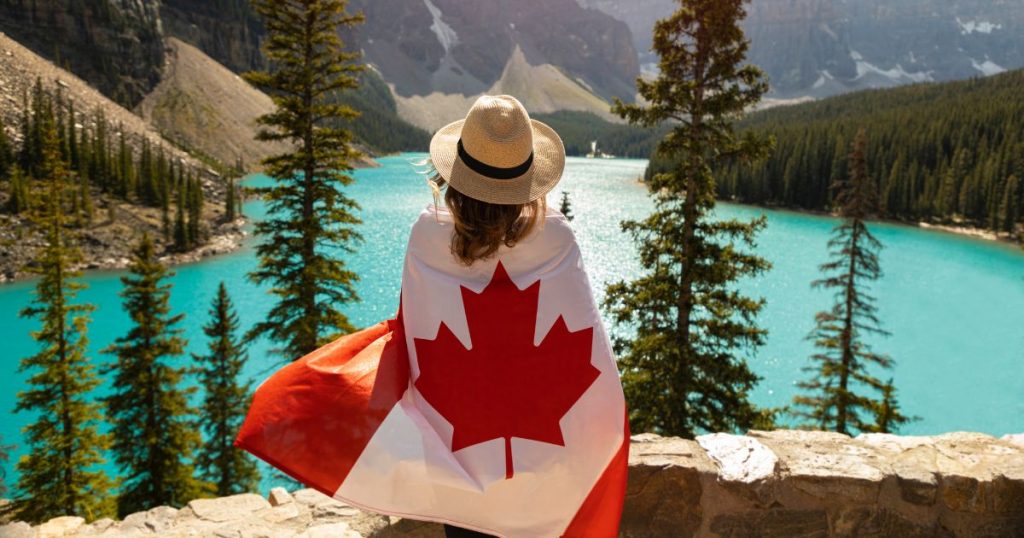 Turista admirando as belezas naturais do Canadá enrolada na bandeira do país
