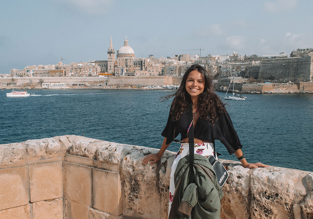 Turista posando para foto com o mar de Malta ao fundo | Intercâmbio na Europa