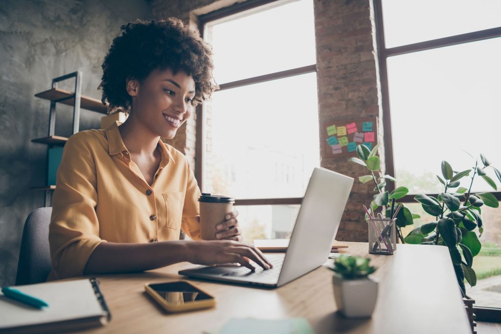 Mulher tomando café enquanto encara a tela do computador | Estudo e trabalho no exterior