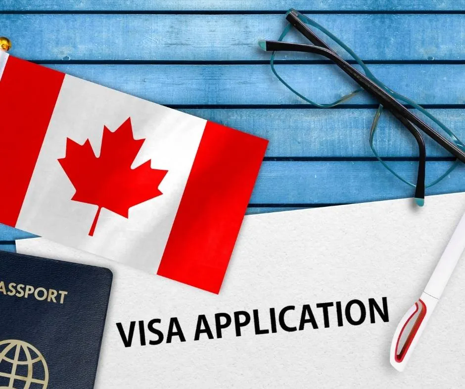 Passaporte, óculos, caneta e uma bandeira do Canadá sobre documento de aplicação de visto | Renovação de visto canadense