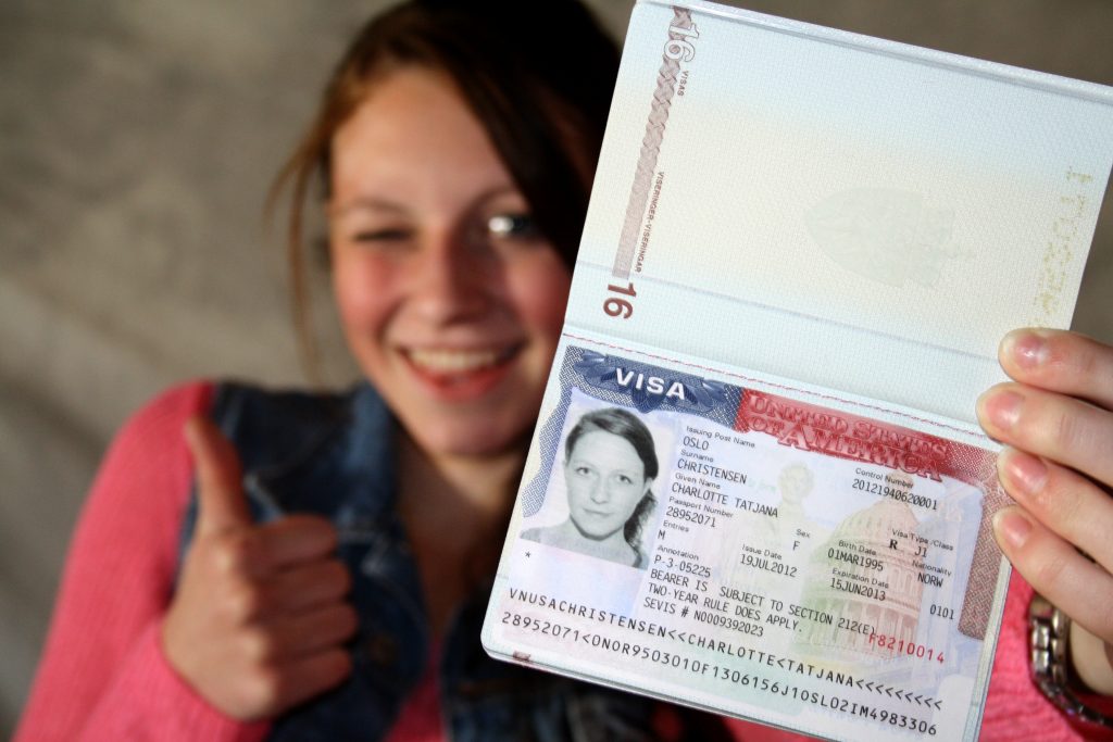 Mulher sorrindo mostrando o visto americano no passaporte