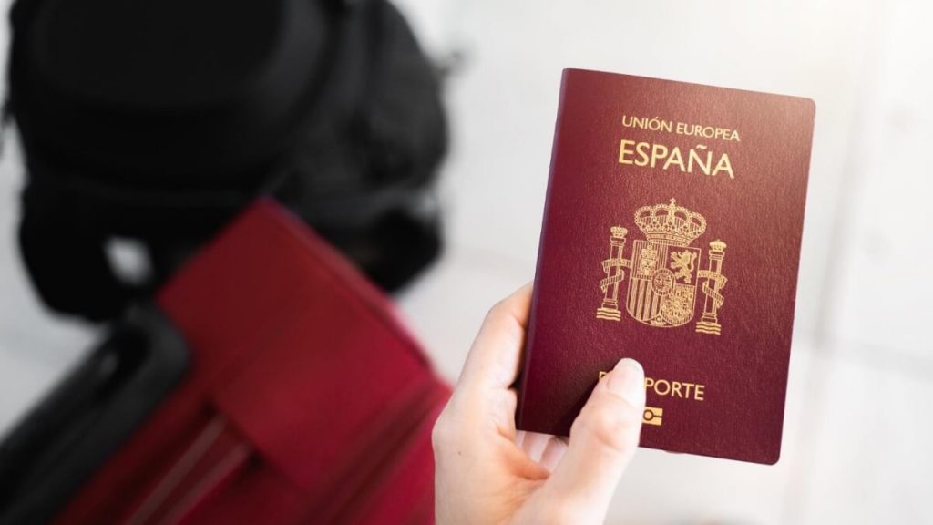 Pasaporte espanhol sendo segurado no aeroporto com duas malas